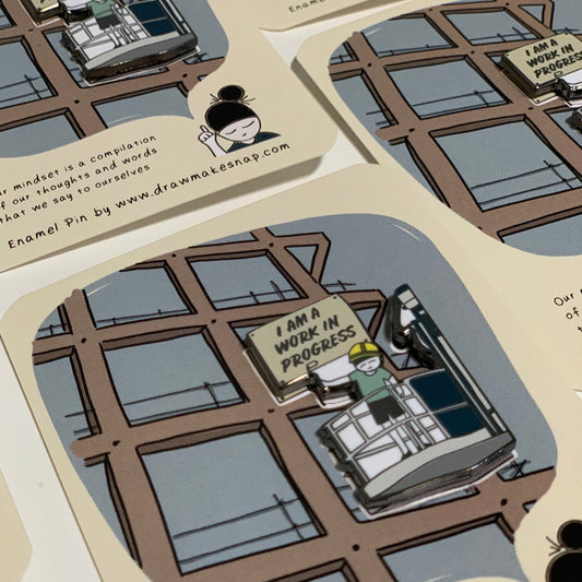 Image shows an enamel pin that says, 'I am a work-in-progress'